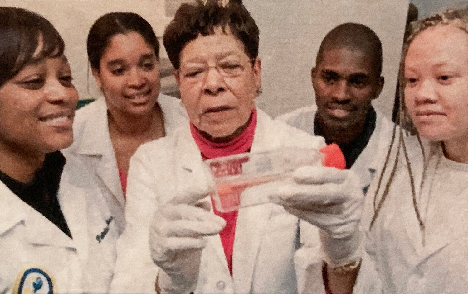 Dolores C. Shockley, PhD, demonstrating the use of a scientific device, flanked by four students